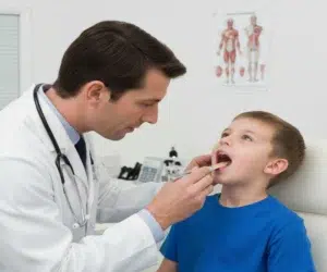 Médico examinando a garganta de uma criança.