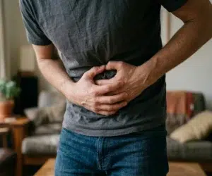 homem segurando a barriga, com dores intestinais.